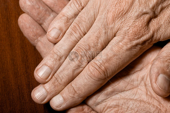 人们棕榈高年长者的彩色相片在黑木背景上交叉手贴细节身体图片