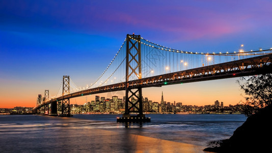 美国加利福尼亚州日落时旧金山天际和湾桥高的地标运输图片