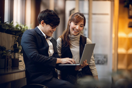 启动在现代工作场所计算机笔记本电脑问题上共同努力对两个男女商人在现代工作场所的双重商业者微笑概念员工项目图片