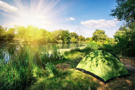 沿河岸绿色旅游帐篷在明日阳光下沿河岸绿色旅游帐篷天太阳空图片