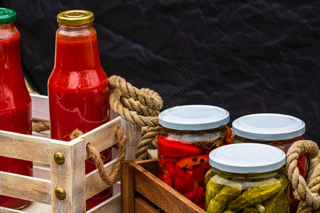 秋天新鲜的配有玻璃罐子木制箱装有咸红胡椒和黄瓜泡菜的玻璃罐头隔离了加罗尔Jars并配有各种咸菜蔬一图片
