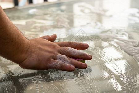 洗女工人使用海绵和清洁喷雾器服务概念家和管理概念的男子清洁玻璃桌图片