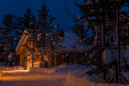 季节芬兰拉普的夜间冬季森林中的小屋白雪夜林中许多地浅色小屋冷杉点亮图片
