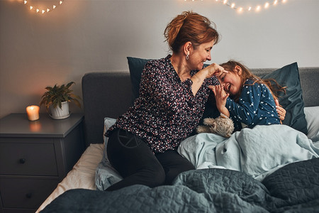 孩子关怀母亲在床上和女儿玩耍在睡觉前得开心妈在睡觉前哭着她可爱的女儿痒幸福图片