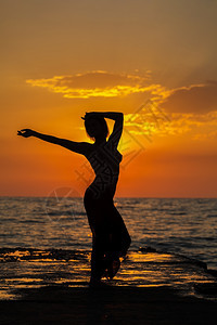 海边夕阳下跳舞的女性图片