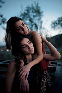 两个年轻女拥抱着在蓝色时分的日落阳光年轻的蓝色图片