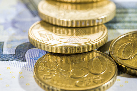 几个欧洲硬币在钞票上为5元黄金硬币价值50欧元硬币和纸账单货支付图片