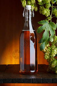 草案贮藏啤酒精瓶在木制桌上有新鲜的绿色香酒图片
