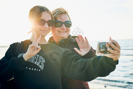暑假旅行时妇女在用视频电话打智能手机时做出势和挥并拍自照片沟通笑社会的图片