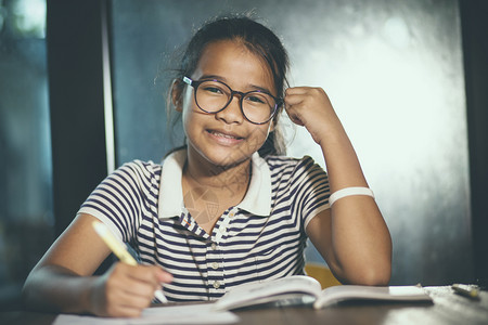 戴眼镜的女人班级身戴眼镜的亚裔青少年在家庭工作时带着堆叠的学校书前台年轻的泰国背景