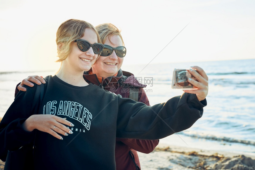 挥手保持打电话快乐女在暑假旅行期间用智能手机打视频电话拍自相片图片