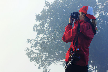 照片摄影师远足妇女穿着红色衬衫站在拍照着图片