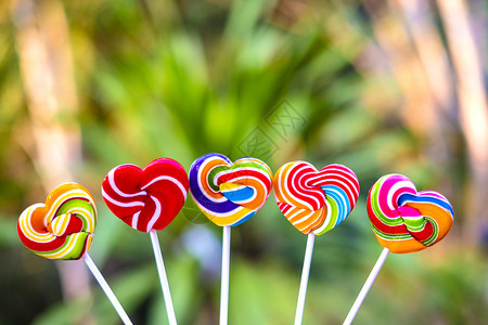 红色的甜糖心形状在模糊背景上满的颜色彩虹棒糖的果情人节礼物爱的概念戳卡片图片