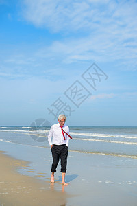 穿正式西装的商人在海滩散步长老景观的图片