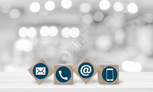 剪下在线的回馈带电话子邮件和纸图标的木立方体在模糊bokeh光背景复制件上白桌子的色边有电话子邮件和政图标背景图片