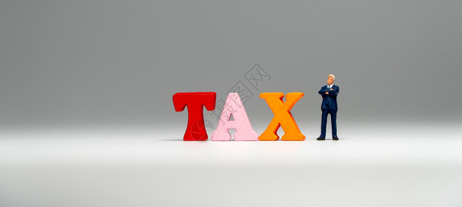 金融可选择的身穿深蓝色西装站在多彩的木制TAX字词和思考abuntTAX旁边收入图片