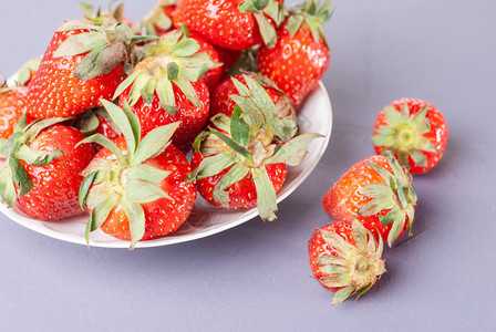 午餐白色盘子紫背景的新鲜草莓紫色背景的红草莓和鲜季节新鲜的图片