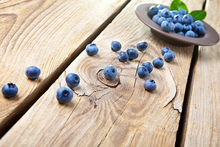 素食主义者棕色的新鲜蓝莓和棕色碗里的叶子一些蓝莓洒在木本底复制空间图片