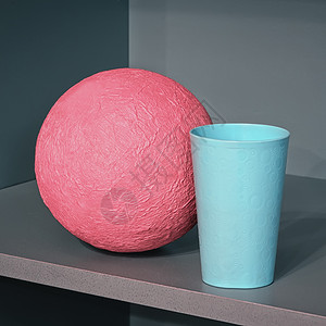 角度抽象的玩具Pinkpapiermache球和在架子角的蓝色塑料杯抽象几何设计有空间复制摘要几何组成与圆形图片
