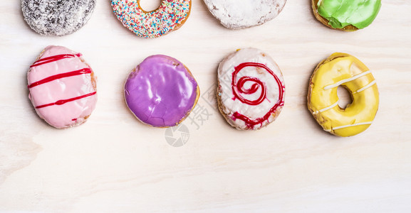 白木背景上彩色新鲜甜圈可口卡路里多于图片