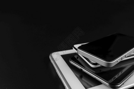 商业高端智能手机堆放在黑桌柜台的智能手机堆叠技术黑色的背景图片