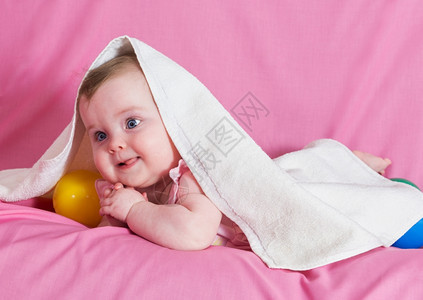粉色的卫生美丽快乐女婴带着粉红背景的白毛巾关心图片