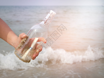 洗过自然手握着瓶子和封装在海边的字母帮助图片