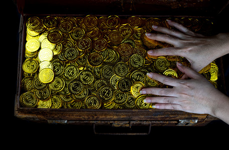 保险箱大量堆叠的金币在女士手中宝箱在黑色背景贫困比特币图片