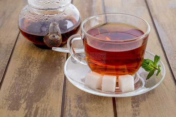 食物一杯加薄荷和茶壶的杯在木制背景上装有薄荷和茶壶一杯加糖和薄荷的新鲜浓茶液体草本植物图片