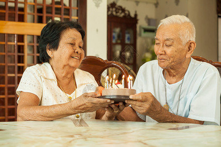 庆典亚洲高龄夫妇在客厅里拿着蛋糕笑活的天图片