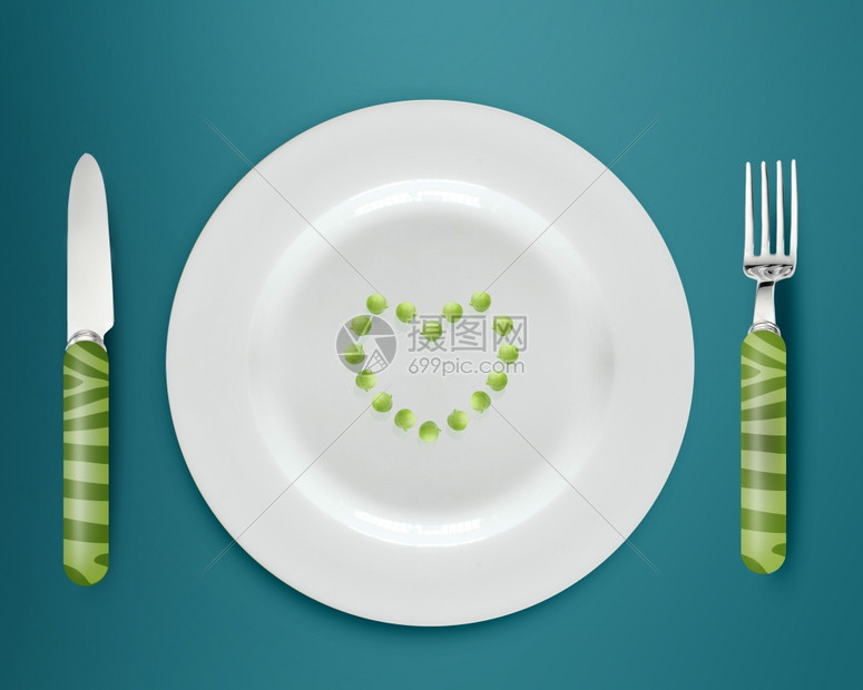 闪亮的晚餐概念白盘上绿色豆子和蓝底的刀叉图片