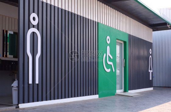 泰国服务卫生间侧视图和关注男残疾人轮椅前景以及木板上女标志和公共厕所绿色墙装饰物上的女标志视角和重点图片