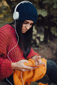 女孩年轻子在森林里用耳机监听音乐甜的牛仔裤图片