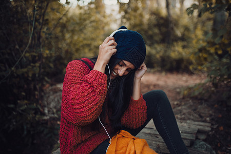 羊毛年轻女子在森林里用耳机监听音乐微笑毛衣图片