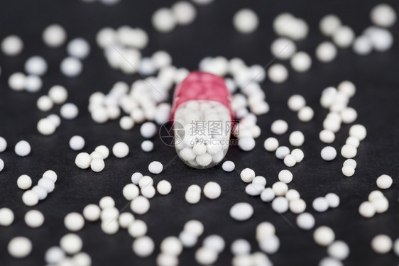 放瘾治愈里面有药物的医胶囊在一张黑纸背景上在胶囊周围内装物散落以小球的形式从其他药片像一个拍照的药品胶囊圆环图片