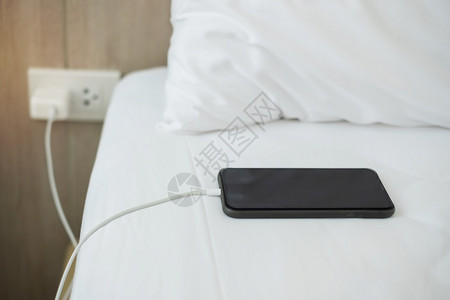 药片沟通在家里卧室的床上用手机智能充电池技术多种分享和生活方式概念在家庭卧室的床上使用多式共享和生活方概念展示图片