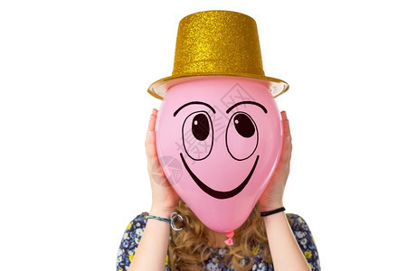 积极的无法识别女孩拿着气球带微笑的面容和金帽子在白色背景中被孤立眼睛图片