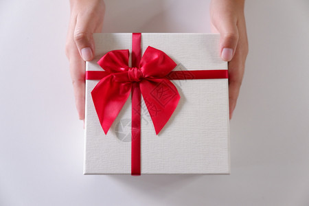 年轻的近身妇女手送白礼盒色带红丝和背景喜庆的假期图片