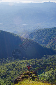 登山者站在顶享受日出高度放松背包图片