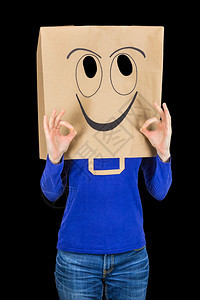 包快乐的女人笑着带纸袋在头上微笑黑色背景上被孤立象征情感图片