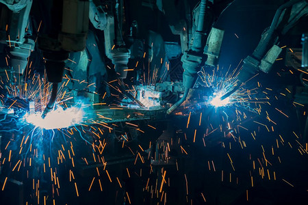 未来派团队工业机器人正在厂焊接汽车部分的行业闪发光图片