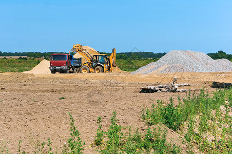 俄罗斯公园一堆沙子旁边的卡车和挖掘机采石场砂一堆沙子旁边的卡车和挖掘机自卸图片