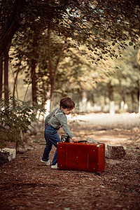 公园里的小男孩拿着旧式手提箱图片