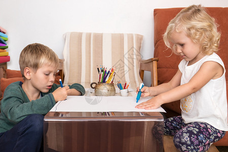 男女儿童在家中有创造时间的纸张上画快乐的学习桌子图片