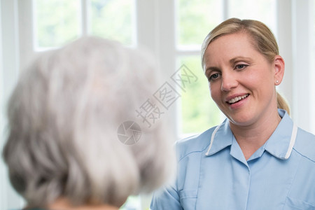 快乐的活在室内家与年长妇女谈话的护理员图片