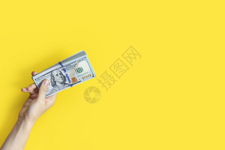 储蓄保持百手拿着一大叠钞票在黄色背景上隔离财富或贷款概念横幅与复制空间手拿着一大叠钞票在黄色背景上隔离财富或贷款概念横幅与复制空图片
