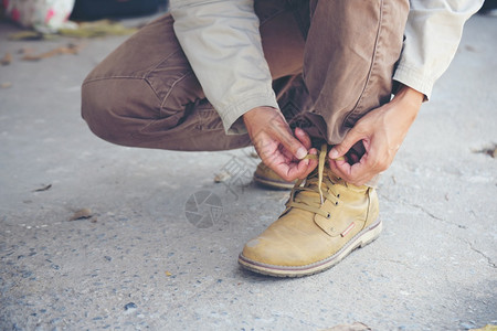 运动男人跪在地上为工人打领带鞋业靴子近距离拍到人手绑鞋的镜头为他建造筑用的棕色靴子紧贴男人把鞋子绑起来用做概念为了类图片