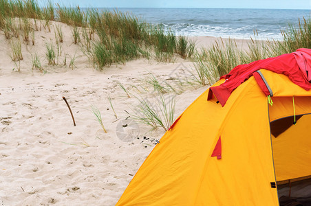 自然沙滩和上的黄色帐篷以及海滩上的火木头齿轮图片