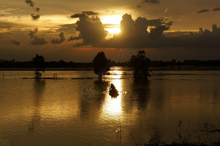 云景观人们在船行上划向太阳前行云层遮掩太阳在河上创造明亮的道路湖图片