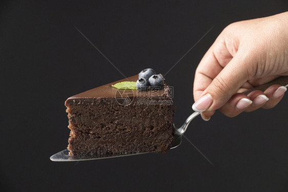 木板白种人职业握着巧克力蛋糕切片的手图片